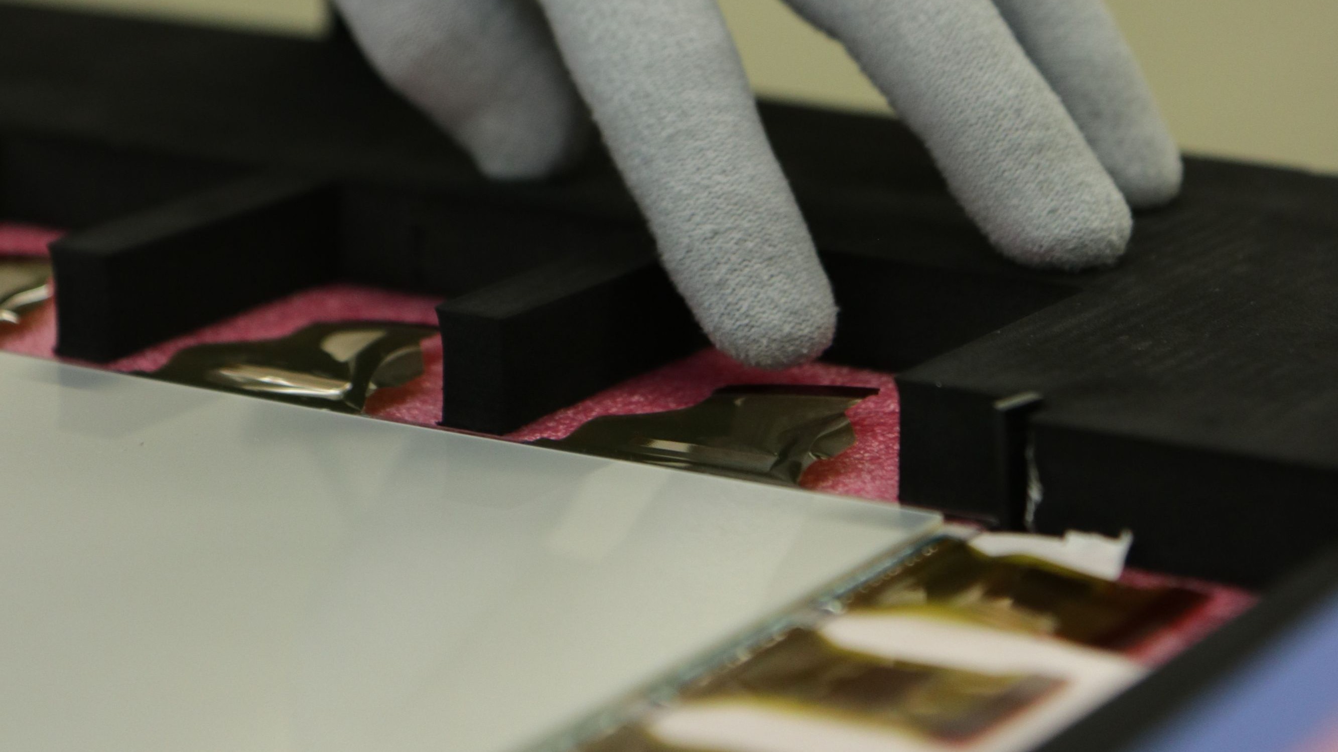 Foto zeigt eine Hand mit Handschuh beim Function Test von Mikroelektronik bei der Wareneingangsprüfung  in unserer Cross Assembly