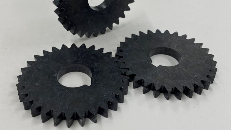 Foto zeigt drei schwarze Zahnräder aus Carbonfaser Composite hergestellt von CrossTEQ